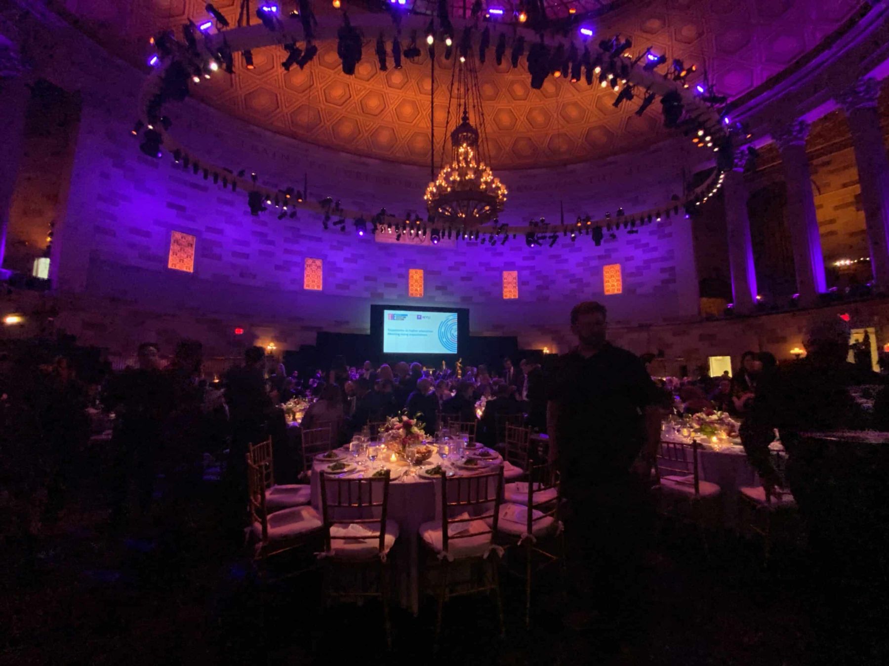 Gala dinner in a grand ballroom with screens