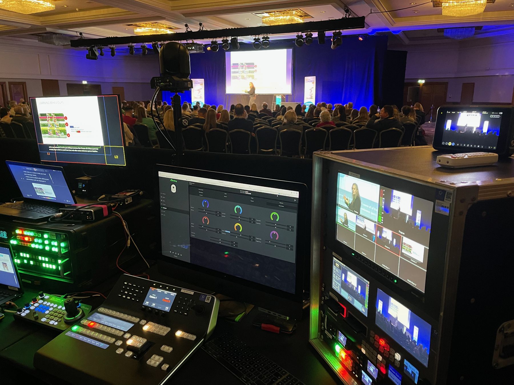 Production desk with vision mixer, looking out over a conference audience